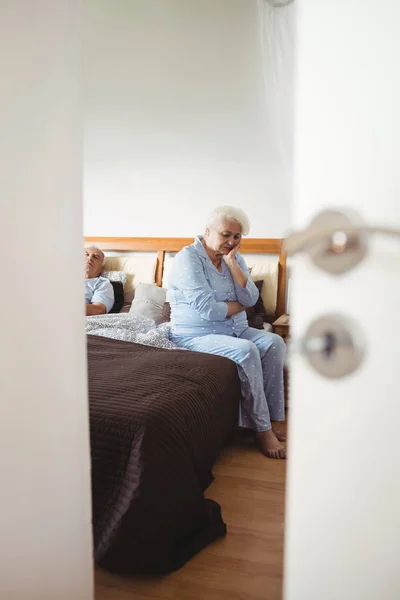 Besorgte Seniorin sitzt auf Bett — Stockfoto