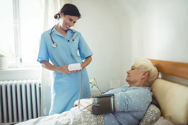Zdravotní sestra a kontrola krevního tlaku starší ženy — Stock fotografie