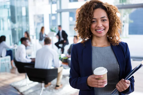 Smiling businesswoman holding coffee in office — Stock Photo, Image