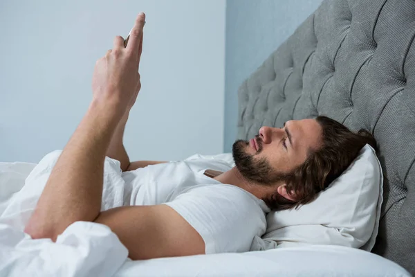 Człowiek przy użyciu telefonu komórkowego w sypialni — Zdjęcie stockowe