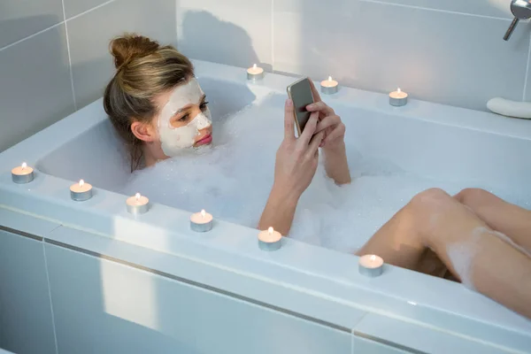 Femme utilisant un téléphone portable tout en prenant un bain — Photo