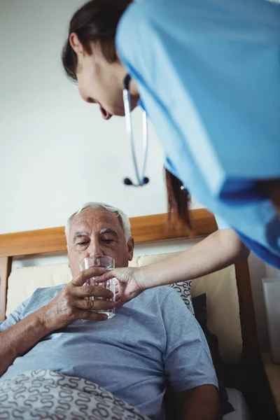 Krankenschwester schenkt Senioren ein Glas Wasser — Stockfoto