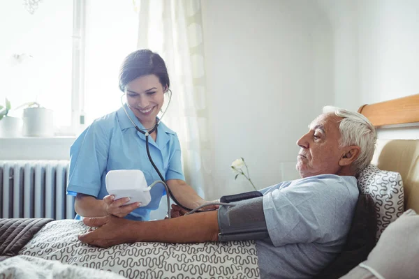 Медсестра проверяет кровяное давление пожилого человека — стоковое фото
