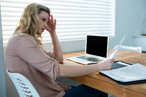 Frau schaut sich Rechnung an, während sie Laptop benutzt — Stockfoto