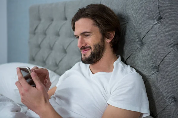 Мужчина с мобильного телефона в спальне — стоковое фото