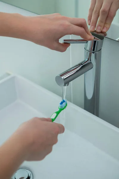 Vrouw wassen tandenborstel onder gootsteen — Stockfoto