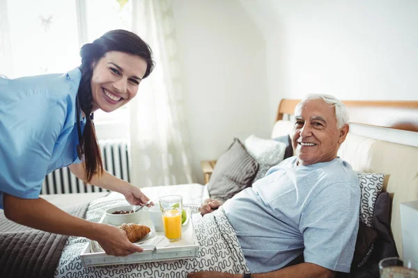 Zdravotní sestra připravuje snídaně pro starší muž — Stock fotografie