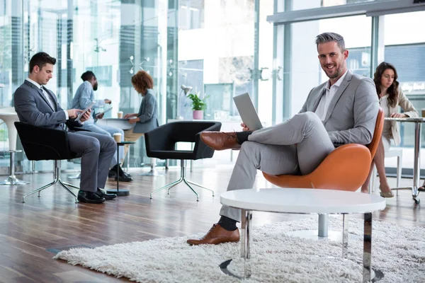Усміхнений бізнесмен використовує ноутбук в офісі — стокове фото