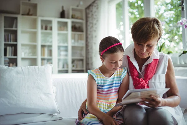 Senior woman and her granddaughter looking at a photo album — Stock Photo, Image