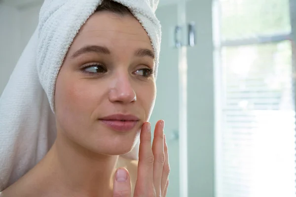Mujer aplicando crema hidratante en su cara — Foto de Stock