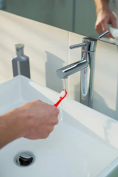 Man zijn tandenborstel wassen onder gootsteen — Stockfoto