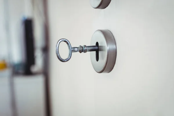 Key on door against blurred background — Stock Photo, Image