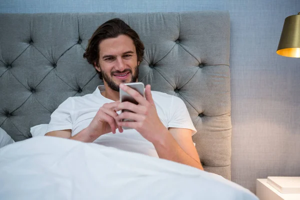 Man använder mobiltelefon i sovrum — Stockfoto