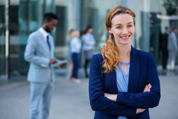 Smiling businesswoman standing with arms crossed — Stock Photo, Image