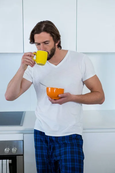Hombre bebiendo café mientras desayuna — Foto de Stock