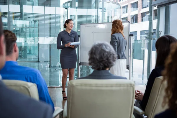 Empresárias discutindo no quadro branco com colegas de trabalho — Fotografia de Stock