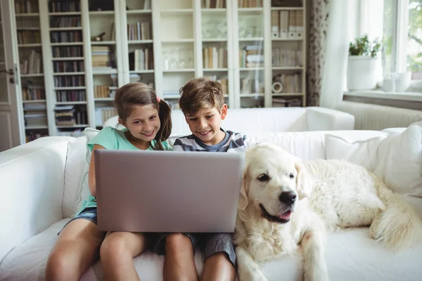 Gyermekek használ laptop, míg a kanapé — Stock Fotó