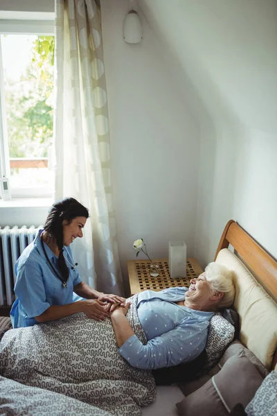 Νοσοκόμα αλληλεπιδρά με ανώτερους γυναίκα στο κρεβάτι — Φωτογραφία Αρχείου