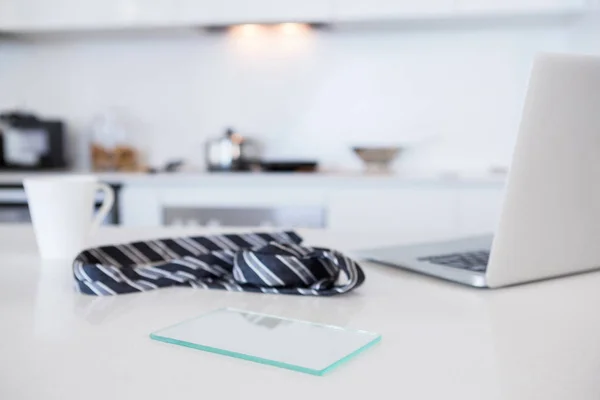 Kravata s hrnek s kávou a laptop v kuchyni — Stock fotografie
