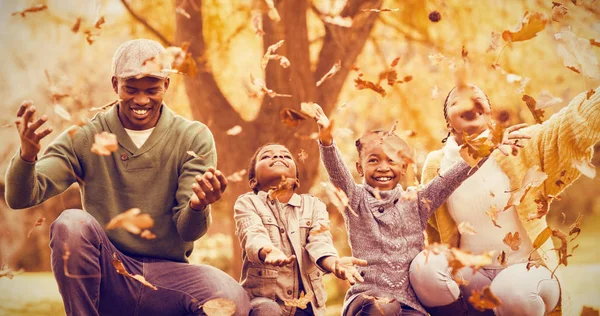 Sonriente familia tirando hojas alrededor — Foto de Stock