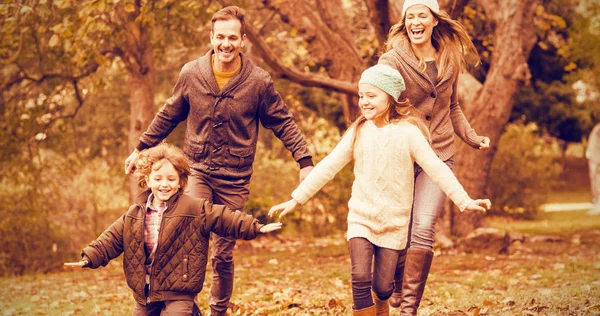 Smiling family running into leaves — Stock Photo, Image