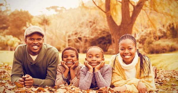 Smiling family lying in leaves — Stock Photo, Image