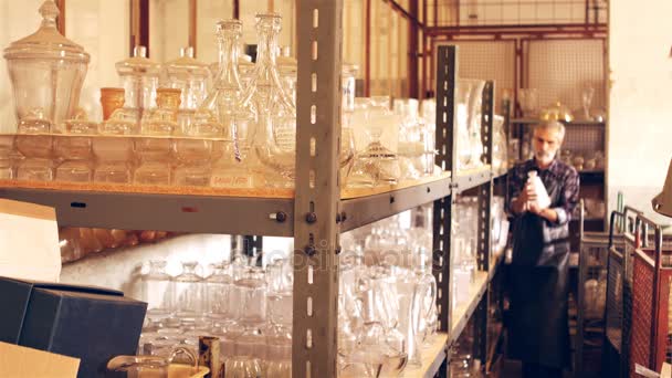 Glassblower arranging glass vase on shelf — Stock Video