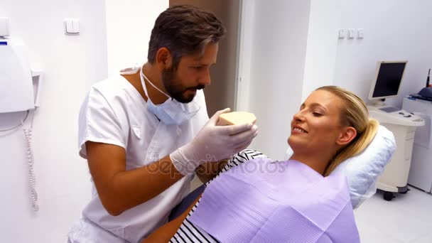 歯科医が患者にモデルの歯を見せて — ストック動画