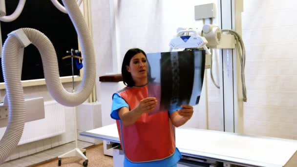 Жінка-лікар, яка вивчає рентгенівський знімок — стокове відео
