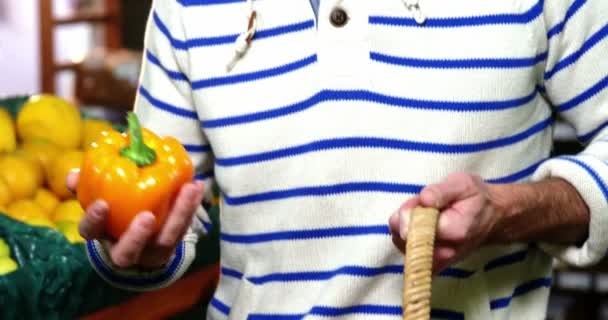 Homem com uma cesta selecionando pimentão na seção orgânica — Vídeo de Stock