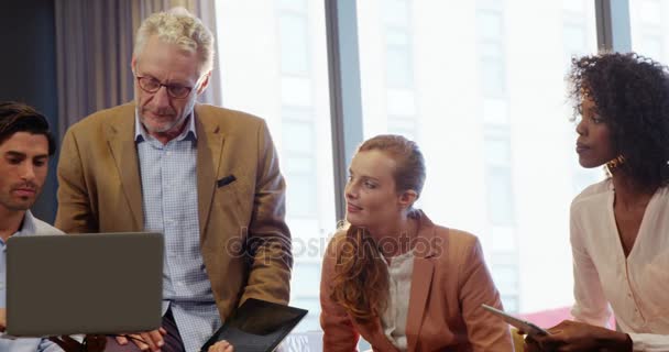 Empresario y compañeros de trabajo discutiendo sobre portátil — Vídeos de Stock