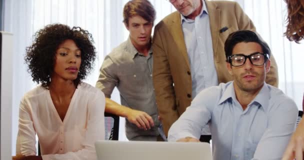 Empresario y compañeros de trabajo discutiendo sobre portátil — Vídeos de Stock