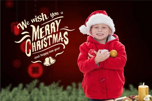 Boy in santa hat holding christmas baubles — Stock Photo, Image