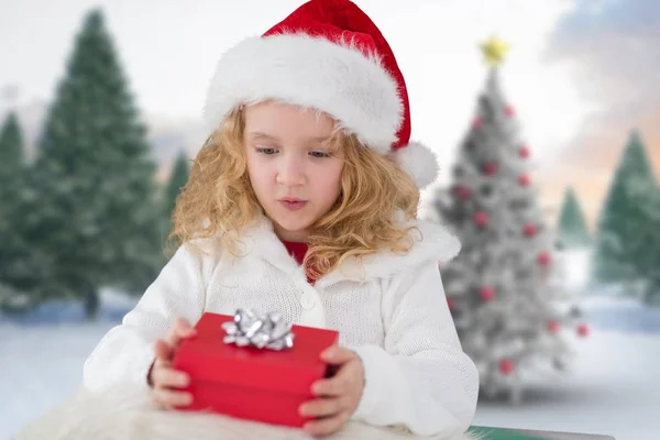 女孩在圣诞老人的帽子，拿着一份礼物 — 图库照片