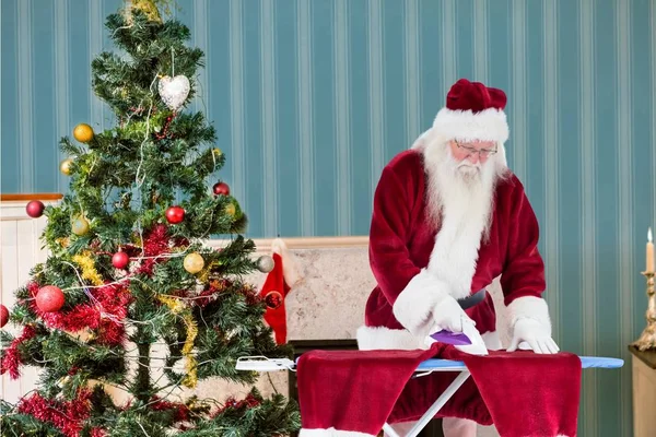 Weihnachtsmann bügelt seine Kleider — Stockfoto