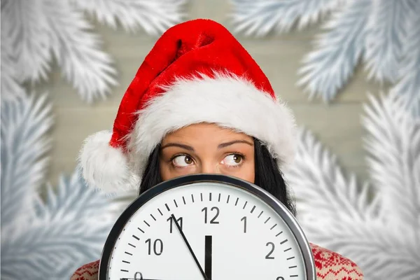 Mujer en santa hat cubriendo la cara detrás del reloj — Foto de Stock