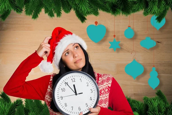 Doordachte vrouw in KERSTMUTS holding klok — Stockfoto