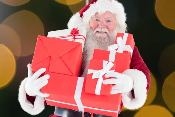Санта-Клаус держит стопку подарочных коробок — стоковое фото