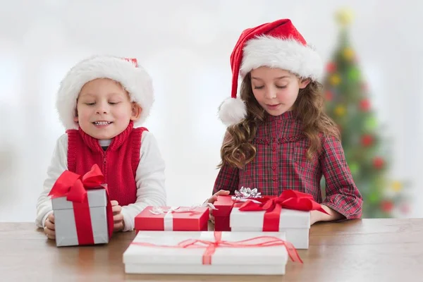 Barn i santa hatt tittar på julklappar — Stockfoto