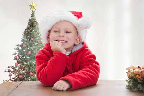 Junge im Weihnachtsmannkostüm lehnt auf Tisch — Stockfoto