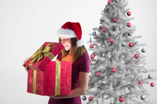 激动的女人，在圣诞老人的帽子，看着礼物 — 图库照片