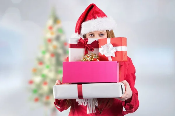 Frau mit Weihnachtsmann-Hut hält Stapel von Geschenken in der Hand — Stockfoto