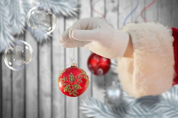 Santa claus holding a christmas bauble — Stock Photo, Image