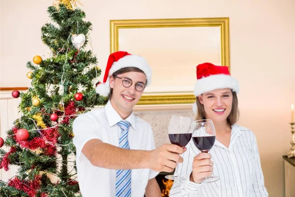 Pareja en santa hat tostadas vino tinto —  Fotos de Stock