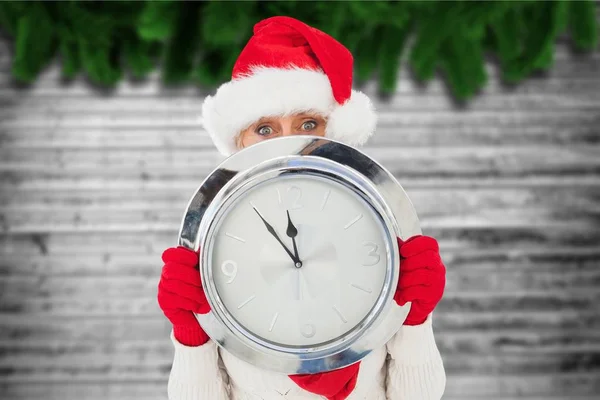 Frau mit Weihnachtsmannhut hält Wanduhr — Stockfoto