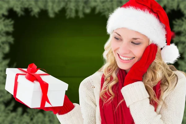 Frau mit Weihnachtsmütze hält Weihnachtsgeschenk in der Hand — Stockfoto