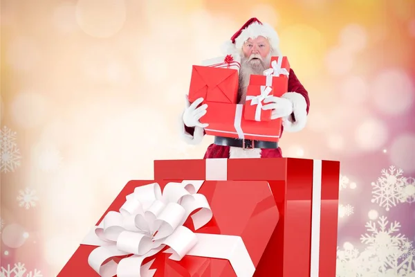 Санта-Клаус держит стопку рождественских подарков — стоковое фото