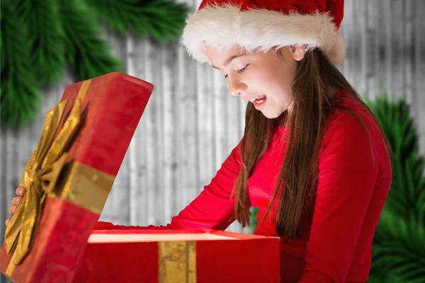 Kobieta w santa hat patrząc na prezent na Boże Narodzenie — Zdjęcie stockowe