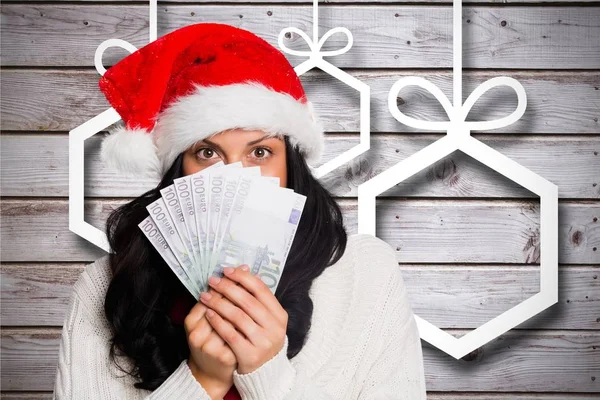 Vrouw in KERSTMUTS holding valuta Opmerking — Stockfoto