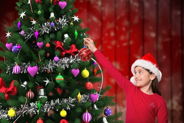 Flicka i santa hatt dekorera julgran — Stockfoto